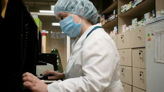 Young asian pharmacist woman holding computer tablet using for checking medication details on a box in pharmacy drugstore.