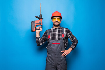 Portrait of bearded handyman with electric drill isolated on blue background