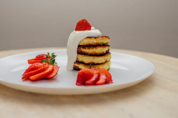 Delicious homemade pancakes with strawberries on plate on a light background
