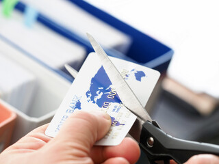 Male hand cutting banking card with scissors
