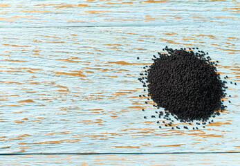black cumin on a blue wooden table, top view with copy space.
