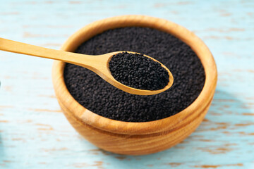 black cumin seeds in a wooden bowl  on a rustic table, close-up.
