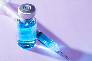 Close-up of a medical bottle with a blue liquid and a syringe