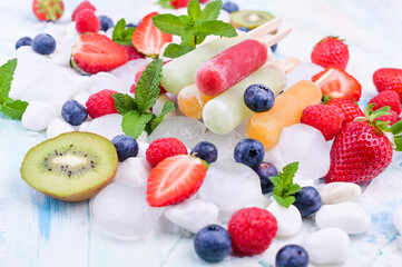 Homemade strawberry popsicles with ice, assorted berries and mint. Summer healthy eating concept with copy space. Fruit ice with different flavors.