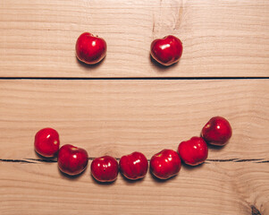 Naklejka na ściany i meble red cherries on wooden background. Smile. Smiling. Funny photo. Wooden background. 