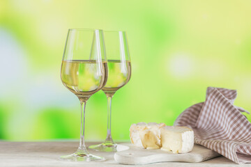 White wine served with cheese plate on light green background. Two wineglasses of vino verde. Seasonal holidays concept