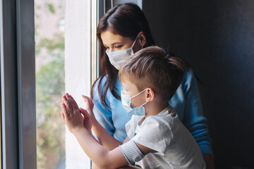 Sad mother and son in protective masks in pandemic quarantine