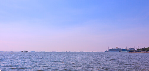 Beautiful sunset colors and sea view with an ocean liner on the horizon in the seaport. Seascape for travel, advertising and holidays backgrounds