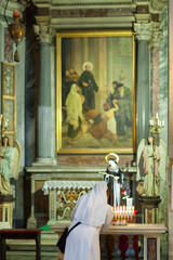 ROME, ITALY - 2014 AUGUST 17. Nun lights a candle in the Church in Rome.
