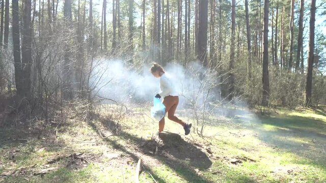 A girl collects garbage in the forest. Environmental pollution. A volunteer removes garbage. cleansing of the nature from plastic.