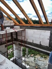 Attic under construction. house in basic state. Wooden roof construction, rafters, blocks and wreath. View of nearings through the roof.