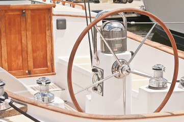 Front view, close distance of a pilot station of a luxury sailboat, with sterring wheel, compass, wood door and automatic cleats