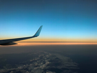 Curved wing tip of a commercial aircraft against a colourful dawn sky. No people. Space for copy.