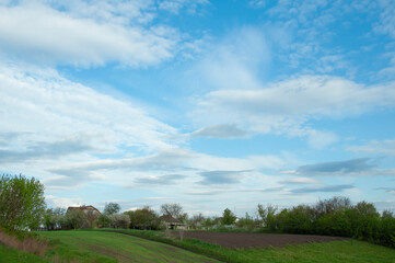 Plowed field in spring against the blue sky and white clouds