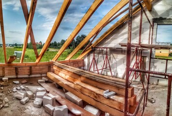 Attic under construction. house in basic state. Wooden roof construction, rafters, blocks and wreath. View of nearings through the roof.
