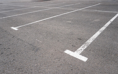Dark asphalt road with marking lines. Tarmac texture. White disabled sign on a empty parking lot. Black tarmac texture with road marking 