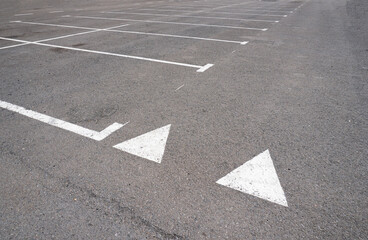 Dark asphalt road with marking lines. Tarmac texture. White disabled sign on a empty parking lot. Black tarmac texture with road marking 