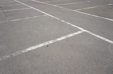 Dark asphalt road with marking lines. Tarmac texture. White disabled sign on a empty parking lot. Black tarmac texture with road marking 