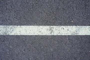 Fototapeta premium Dark asphalt road with marking lines. Tarmac texture. White disabled sign on a empty parking lot. Black tarmac texture with road marking 