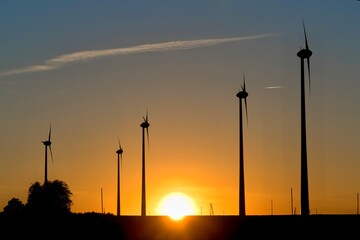 Fototapeta na wymiar Field of wind generators at sunset. Great sun on the horizon.
