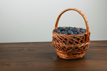 Fototapeta na wymiar blueberry berries in wicker basket on wood table with copy space