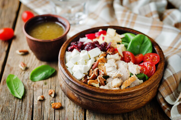 Chicken spinach apple tomato goat cheese salad in a bowl