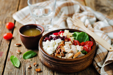 Chicken spinach apple tomato goat cheese salad in a bowl