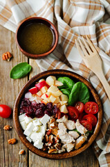 Chicken spinach apple tomato goat cheese salad in a bowl