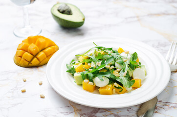 Avocado mango arugula pine nuts Mozzarella salad in a plate