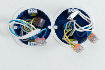 The wall is of light-colored plaster and has several outlets. Preparation for installing an outlet, wires protrude, installing electrical outlets.