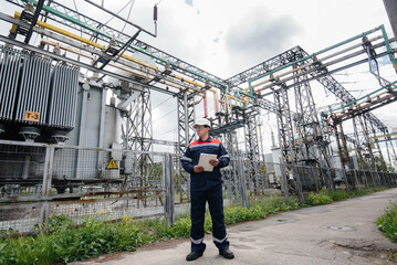 Naklejka na ściany i meble The energy engineer inspects the equipment of the substation. Power engineering. Industry