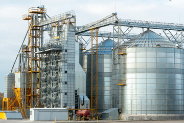 A large modern plant for the storage and processing of grain crops. view of the granary on a sunny day. Large iron barrels of grain against the sky. End of harvest season.