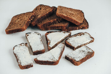 Sliced of brown bread with butter on a white wooden background. Top view. Copy, empty space for text