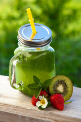 Detox smoothie and fruit on wooden table in the garden with fruit.