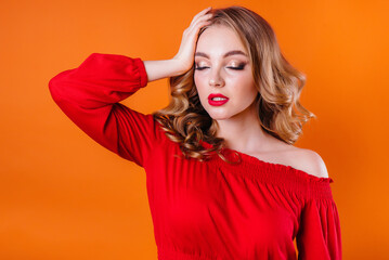 A young beautiful girl shows emotions and smiles in the Studio on an orange background. Girls for advertising