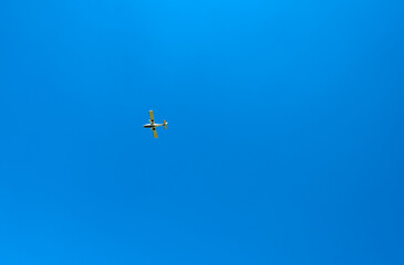 Small light aircraft flying against a deep blue sky