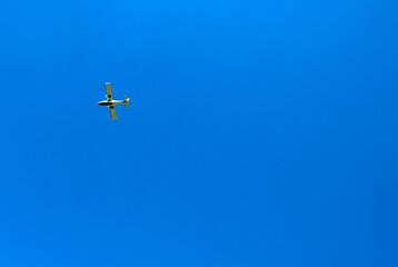 Small light aircraft flying against a deep blue sky