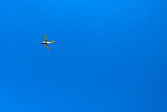 Small light aircraft flying against a deep blue sky