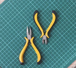 different technician tools and items for fixing or repairing  things on dark green checked grid...