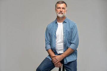 Portrait of a casual senior sitting on a chair on white background.