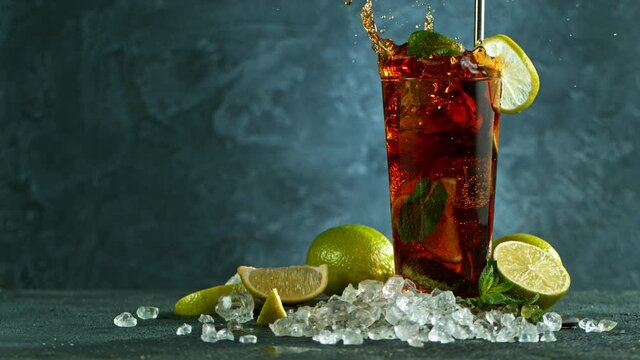 Refreshing Cuba libre cocktail in a glass on black stone table, macro super slow motion filmed on high speed cinematic camera.