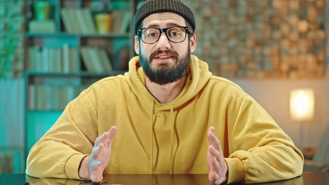 In front of the camera concentrated young man explain charismatic something in front of the camera gesticulating with hands he have a online webinar