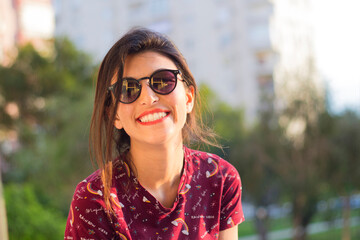 Portrait of beautiful woman facing the park and smiling at sunset