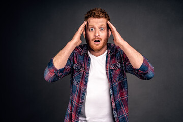 Frustrated gloomy redhead male in shirt, holding head and staring with disappointment at camera, losing bet, feeling devestation and regret, standing over gray background unhappy