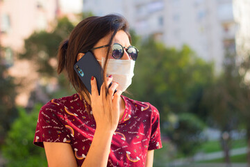 The girl is talking on the phone. The girl in the mask.