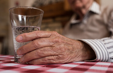 Old man holding glass of water