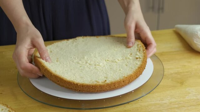 Close up of woman hands making sweet cake with white cream and biscuit.