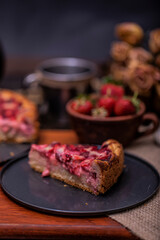 Pie with rhubarb and organic strawberries on a dark wooden background with fresh strawberries. Selective focus and vintage image.