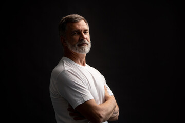 Obraz premium Portrait of smiling mature man standing on black background.