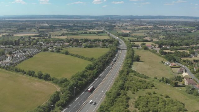 Aerial view of cars driving on scenic highway through green countryside landscape